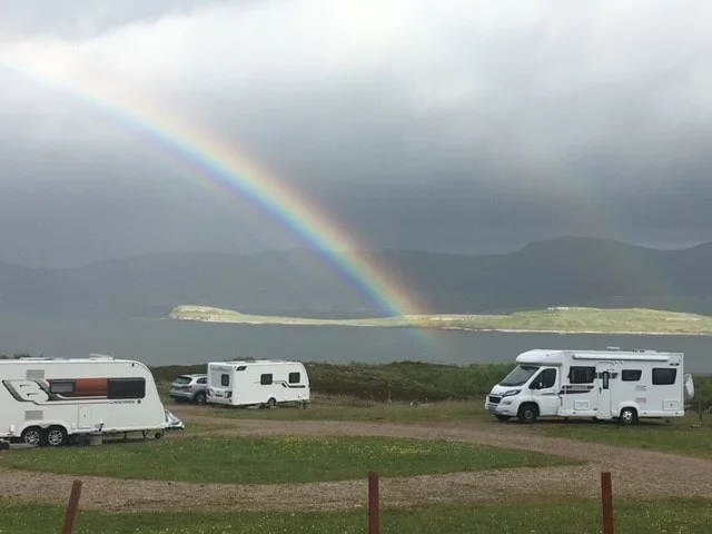 Group of van lining up near a rainbow